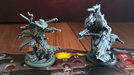 Two Hunter miniatures from Grimcoven on a character dial, all on a wooden surface