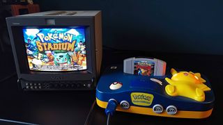 Pokemon Stadium on Sony PVM CRT next to Pikachu N64 console on black desk.